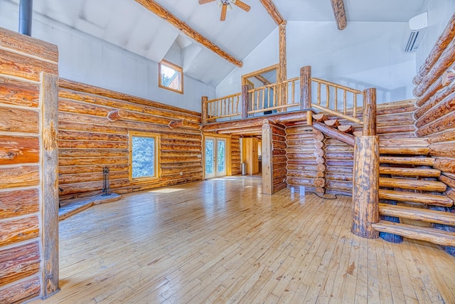 unfurnished living room with rustic walls, beamed ceiling, and high vaulted ceiling