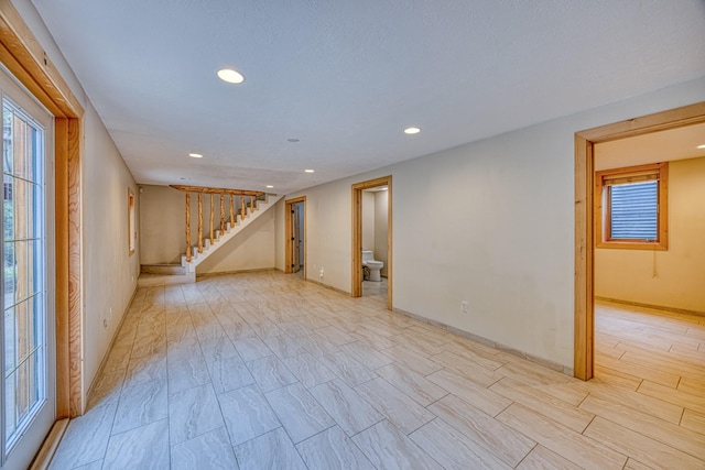 basement featuring baseboards, stairs, recessed lighting, and plenty of natural light