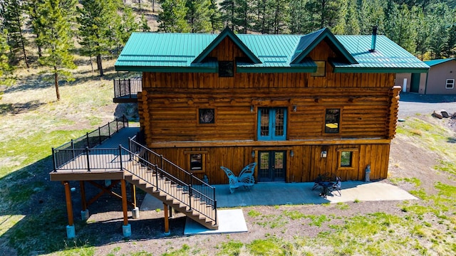 rear view of house featuring a patio area, log siding, french doors, and stairs