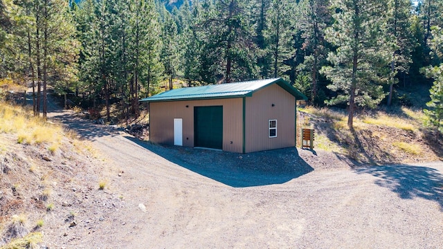 view of outdoor structure featuring a wooded view and an outbuilding