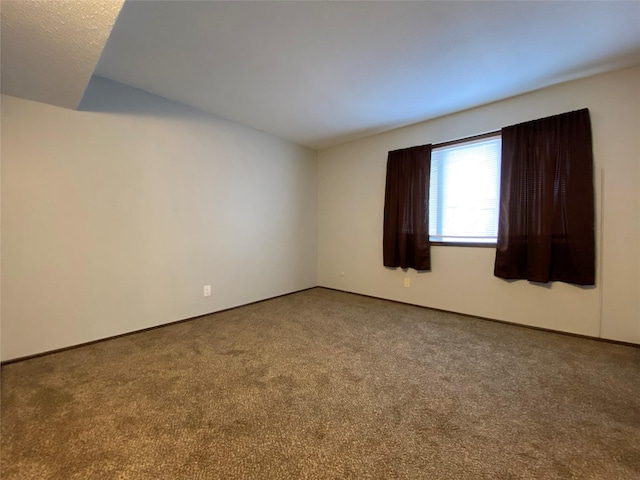 unfurnished room with baseboards, vaulted ceiling, and carpet