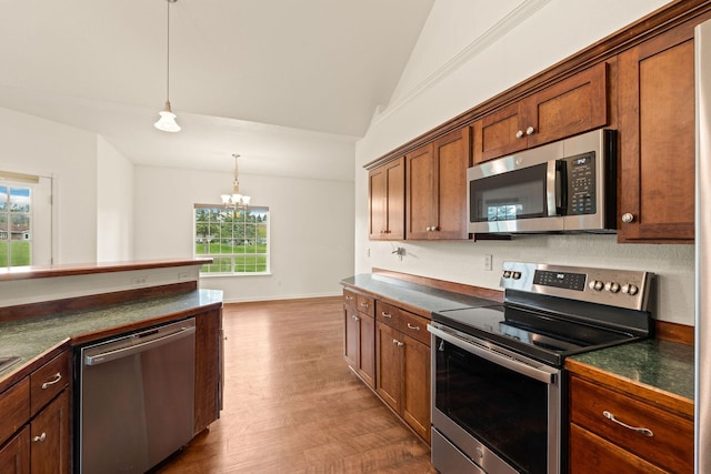 kitchen with dark countertops, appliances with stainless steel finishes, vaulted ceiling, and a healthy amount of sunlight
