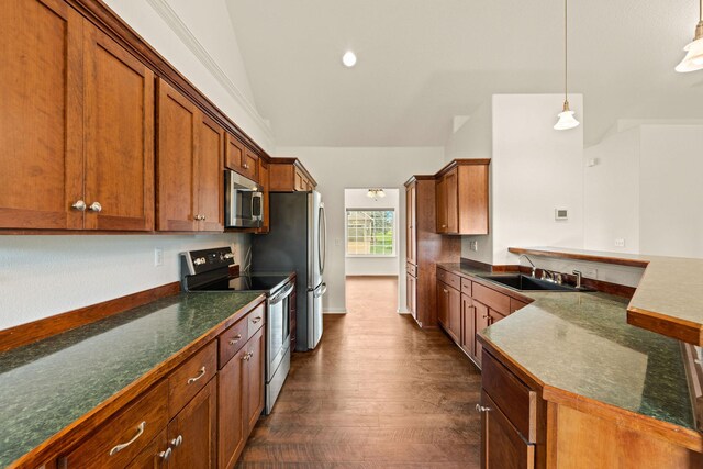154 Palmer Dr, Kalispell, MT 59901 - kitchen featuring brown cabinetry, appliances with stainless steel finishes, dark countertops, vaulted ceiling, and a sink