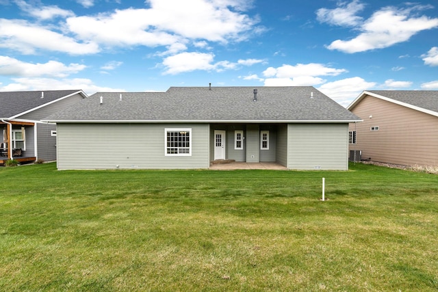 back of house featuring a lawn, a shingled roof, and a patio area