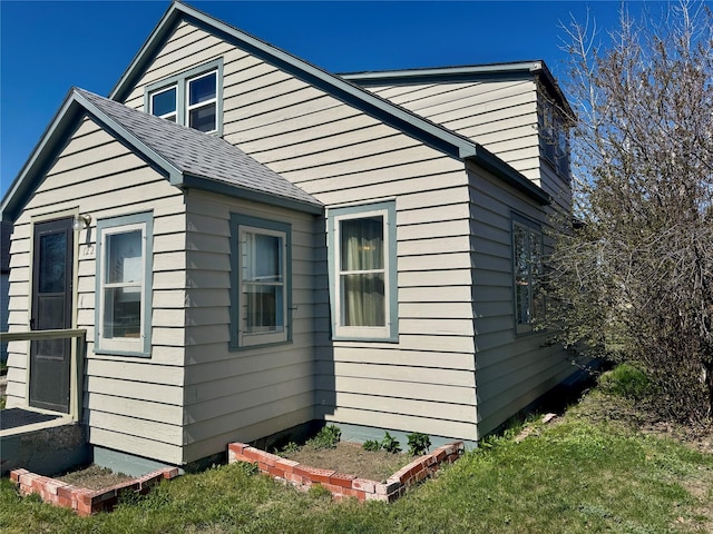 view of property exterior featuring a shingled roof and a yard