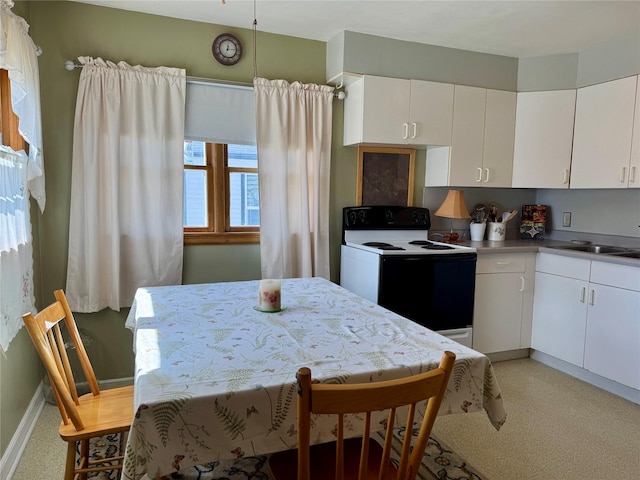 kitchen with electric range, baseboards, light colored carpet, white cabinetry, and a sink