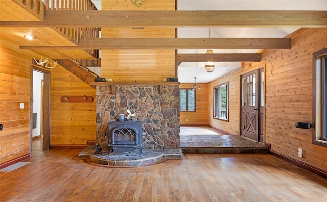 unfurnished living room featuring baseboards, wood walls, and wood finished floors