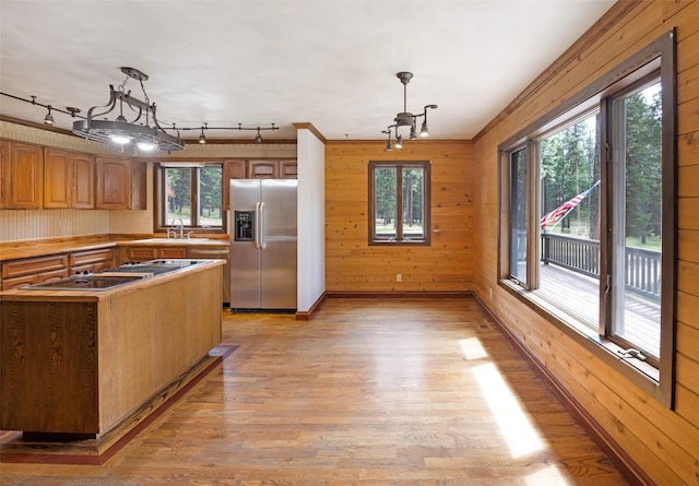 kitchen featuring an inviting chandelier, wood walls, light wood-type flooring, rail lighting, and appliances with stainless steel finishes