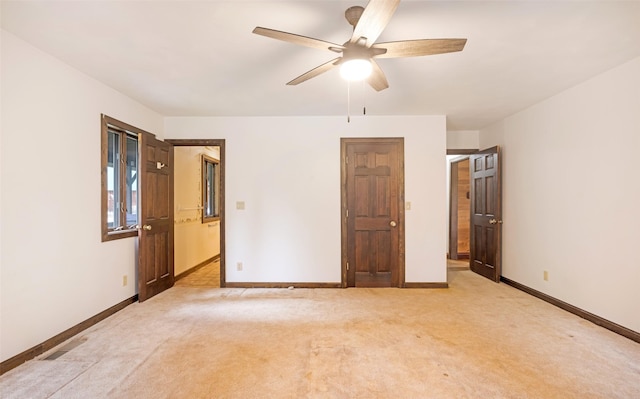unfurnished room featuring a ceiling fan, baseboards, and light colored carpet
