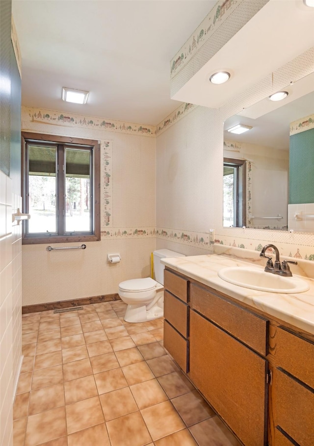 bathroom featuring toilet, wallpapered walls, a wainscoted wall, and vanity