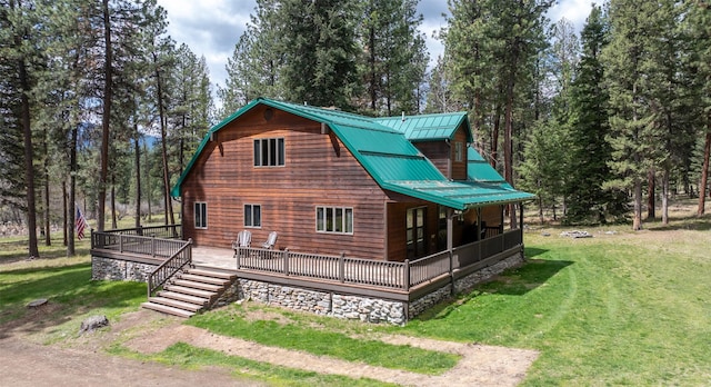 exterior space featuring a lawn, a wooden deck, and metal roof