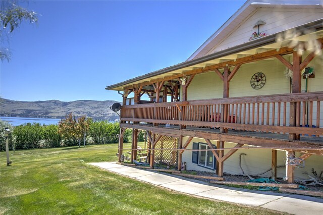 rear view of house featuring a yard and a deck with water view