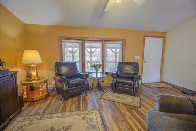 living area with baseboards, a ceiling fan, and wood finished floors