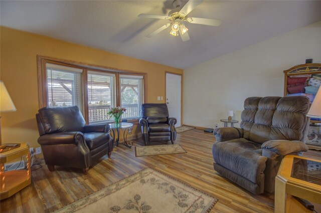 living room with a ceiling fan, wood finished floors, and lofted ceiling