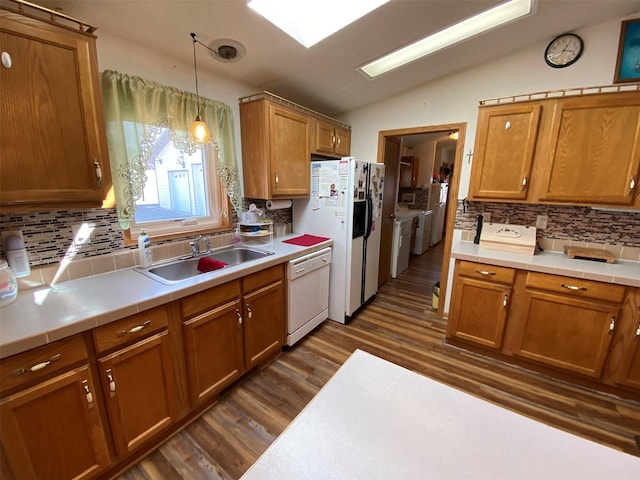 kitchen featuring lofted ceiling, white appliances, tasteful backsplash, a sink, and dark wood finished floors