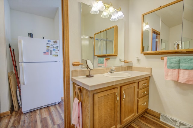 bathroom featuring visible vents, decorative backsplash, wood finished floors, and an inviting chandelier