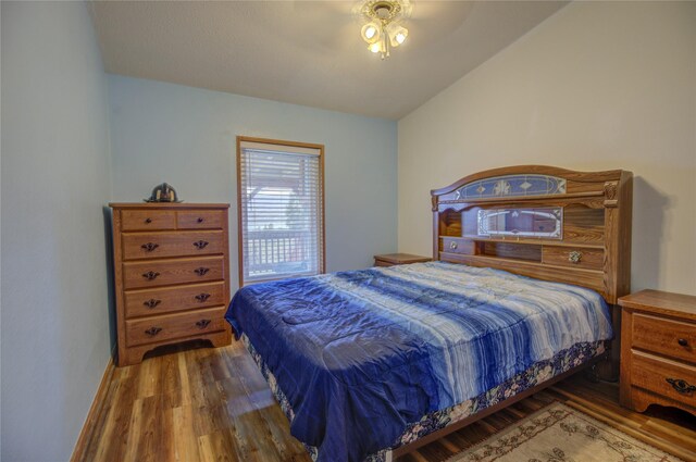 bedroom with wood finished floors and vaulted ceiling