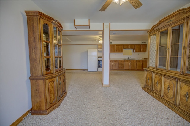 interior space with a ceiling fan, baseboards, light carpet, and a sink