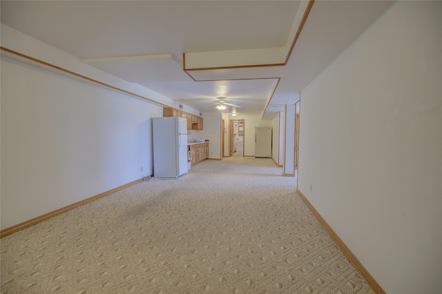 interior space featuring baseboards, light colored carpet, and ceiling fan