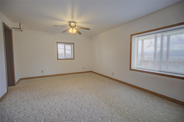 unfurnished room with baseboards, a ceiling fan, and light colored carpet