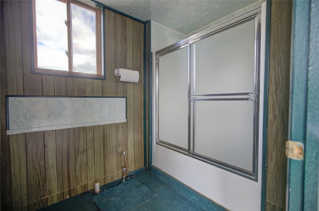bathroom featuring wood walls and an enclosed shower