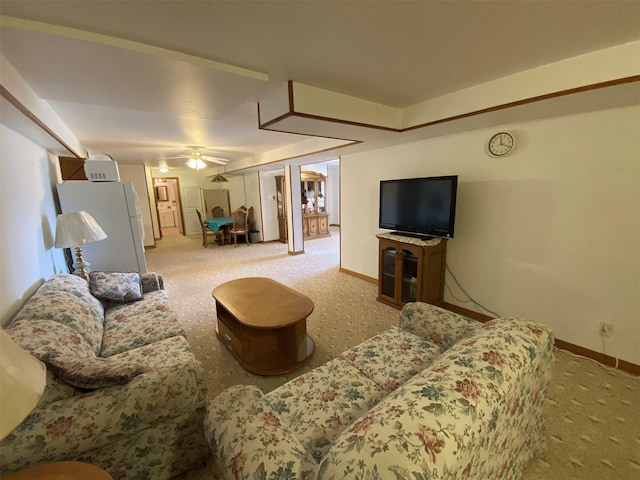 carpeted living area with baseboards and a ceiling fan