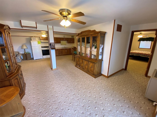 interior space with baseboards, a ceiling fan, and light carpet