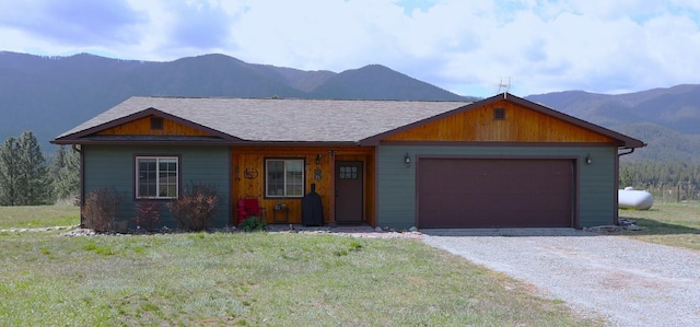 single story home featuring driveway, a front lawn, a mountain view, and a garage