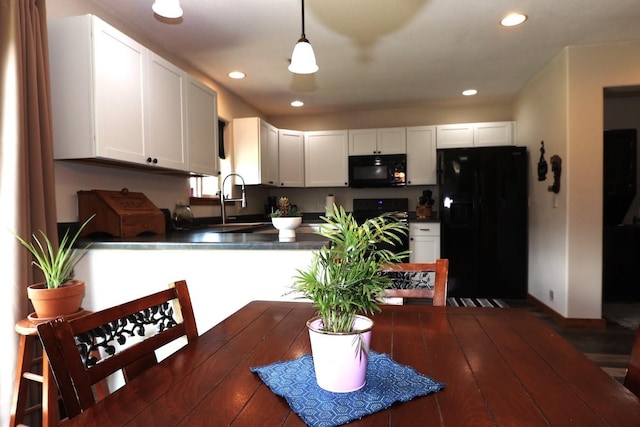 kitchen featuring white cabinets, a peninsula, black appliances, and dark countertops