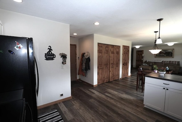 kitchen featuring dark countertops, baseboards, freestanding refrigerator, dark wood-style floors, and recessed lighting