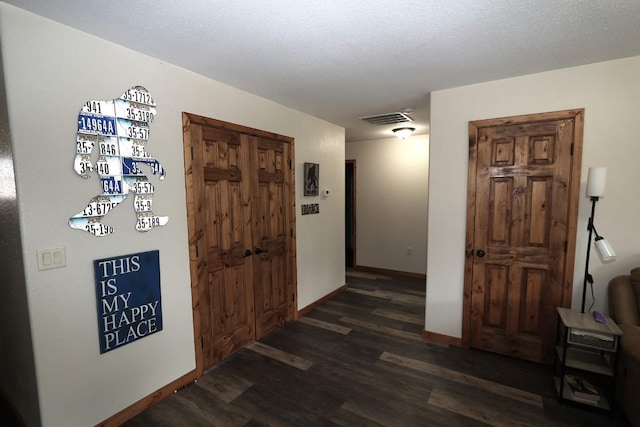 hall with baseboards, visible vents, and dark wood finished floors
