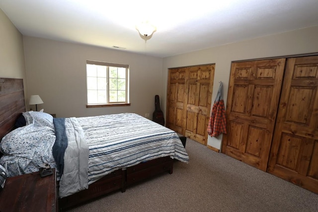 bedroom with carpet floors, two closets, and visible vents