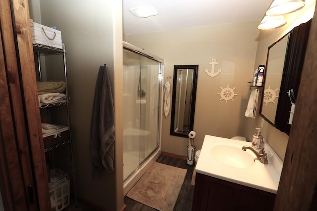 full bath with vanity, a stall shower, and wood finished floors