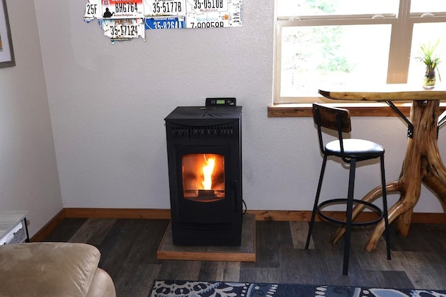 room details featuring baseboards, a wood stove, and wood finished floors