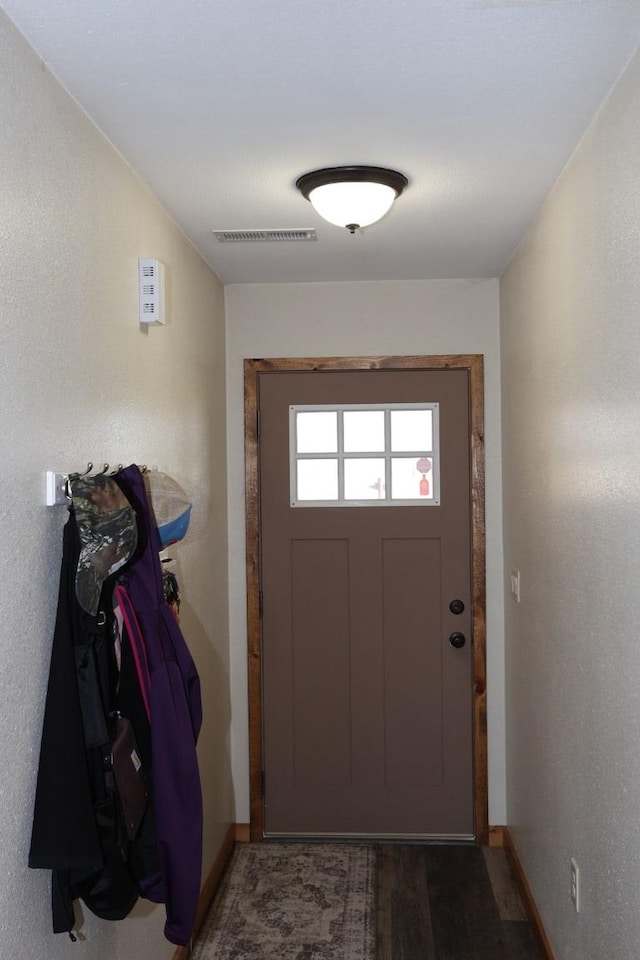entryway with baseboards, visible vents, and wood finished floors