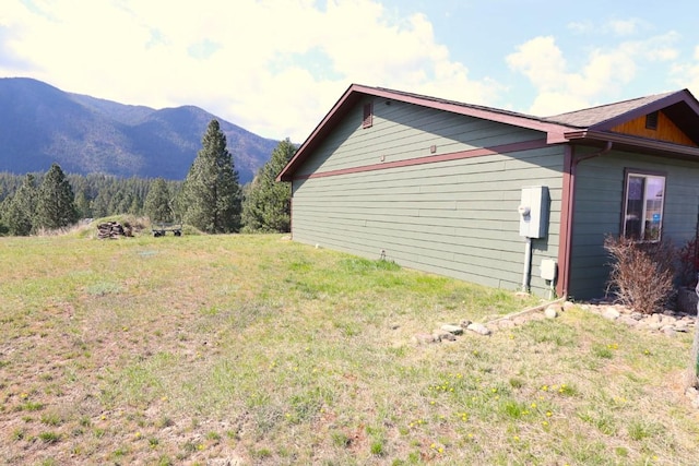 view of side of property with a mountain view and a yard