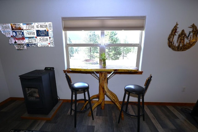 dining room with baseboards, a wood stove, and wood finished floors