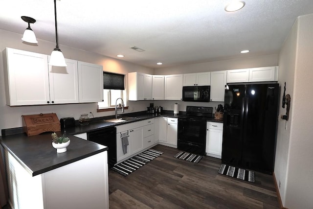 kitchen with white cabinets, dark countertops, a sink, a peninsula, and black appliances
