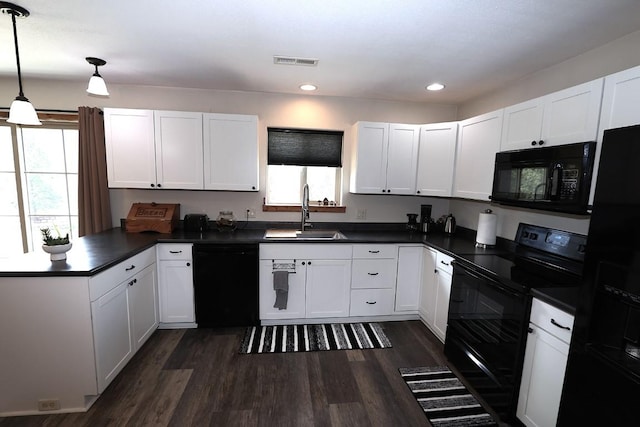 kitchen featuring dark countertops, a sink, a peninsula, visible vents, and black appliances