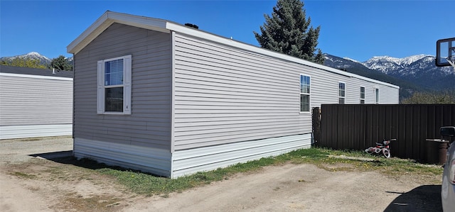 view of side of home featuring a mountain view and fence