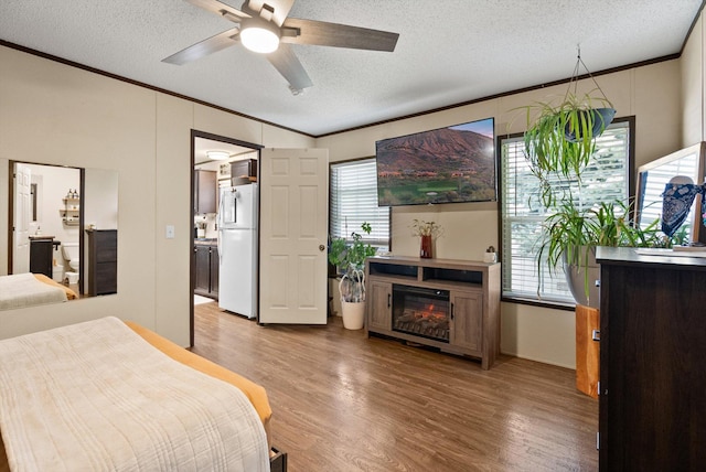 110 Van Sant Rd Unit 4, Kalispell, MT 59901 - bedroom with freestanding refrigerator, ornamental molding, light wood-style floors, a textured ceiling, and a glass covered fireplace