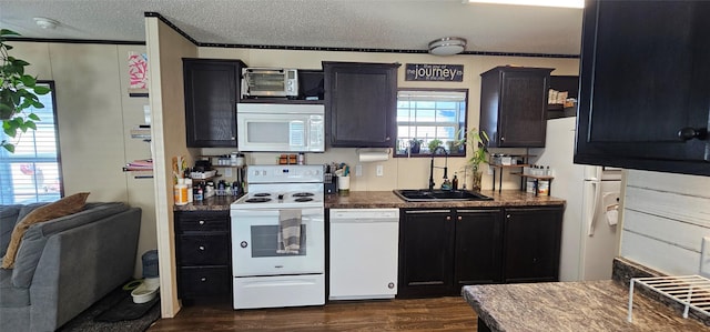 kitchen featuring dark wood-style flooring, white appliances, a textured ceiling, dark cabinets, and a sink