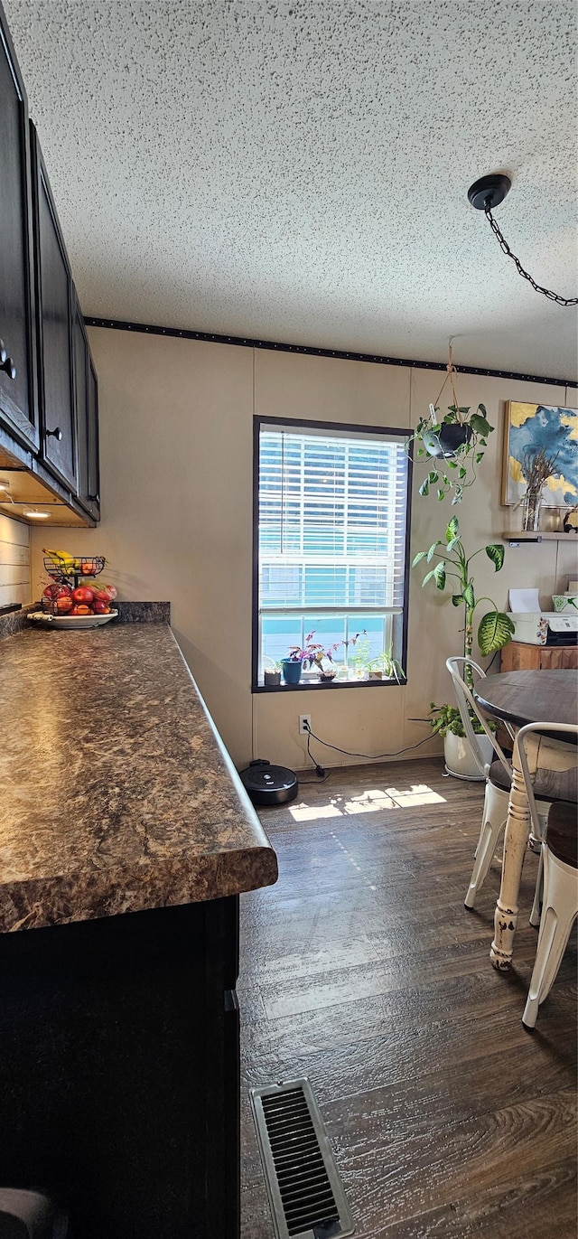 dining area featuring visible vents, a textured ceiling, and dark wood-style floors
