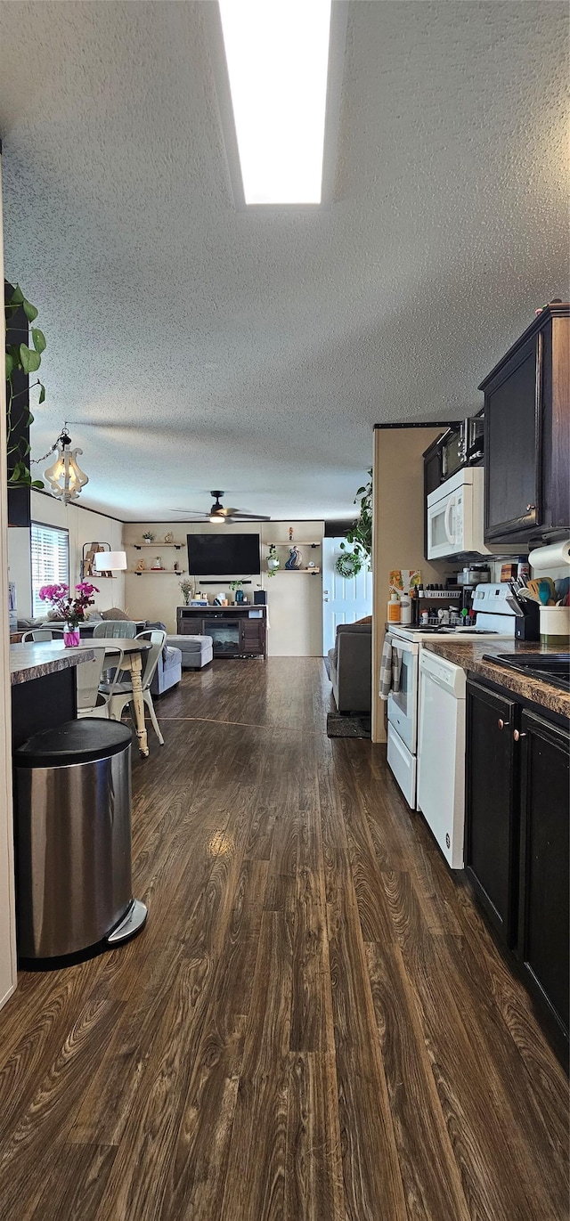 kitchen featuring a textured ceiling, range, white microwave, and dark wood-style floors