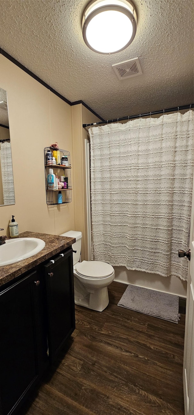 full bathroom with a textured ceiling, visible vents, wood finished floors, vanity, and toilet