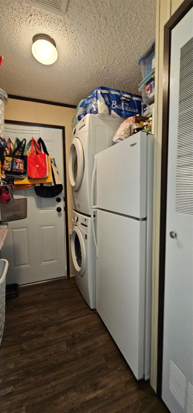 laundry room featuring a textured ceiling, laundry area, stacked washer / dryer, and dark wood-type flooring