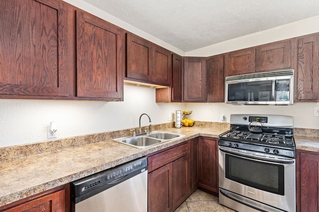 kitchen with a sink, appliances with stainless steel finishes, light tile patterned flooring, and light countertops