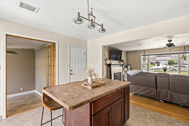 kitchen featuring visible vents, open floor plan, ceiling fan, and light wood-type flooring