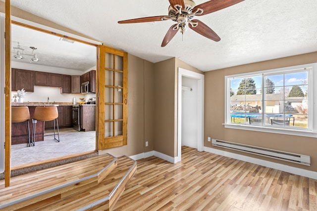 unfurnished living room with a textured ceiling, light wood-type flooring, ceiling fan, and a baseboard radiator