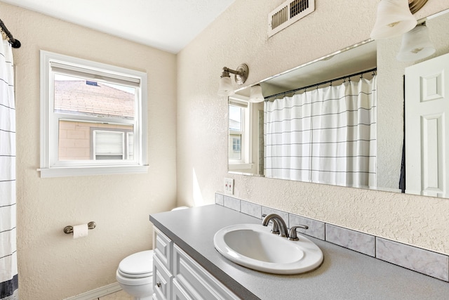 bathroom featuring plenty of natural light, a textured wall, toilet, and visible vents